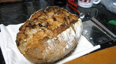 A loaf of sourdough rye with walnuts resting on a napkin atop a kitchen counter