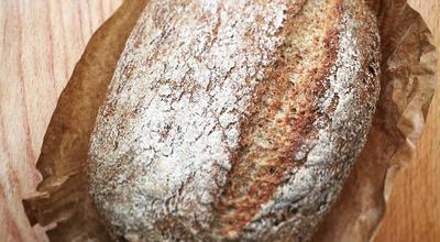 A loaf of bread resting on a rustic wooden table, showcasing its golden crust and inviting texture